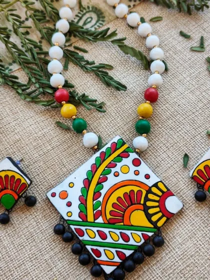 The same diamond-shaped pendant necklace, with a clean white background that makes the colorful motifs pop.