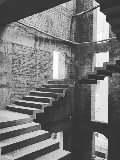 The beauty of a bare shell. This black and white photograph of a staircase well during construction highlights the raw, sculptural quality of the building's form before the final finishes are applied. It reveals the honest structure and the path of light through the space.
