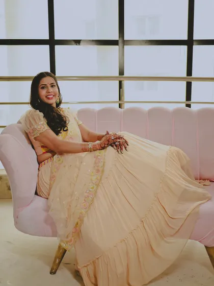 A beautiful solo portrait of the bride seated on a pink sofa, looking elegant and happy.