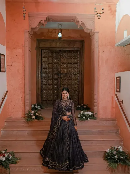 A full-length portrait of the bride standing at the top of a grand staircase in a heritage location.