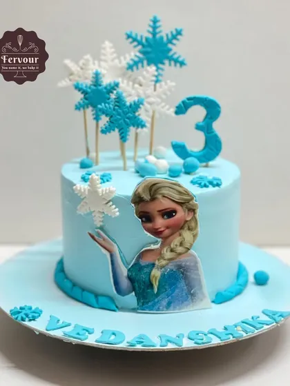 A magical Frozen theme cake for a 3rd birthday. This salted caramel chocolate cake is decorated with an Elsa topper and delicate fondant snowflakes.
