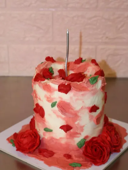 A custom birthday cake that matches your vibe. This one features a rustic, textured finish with bold red buttercream roses and petals.