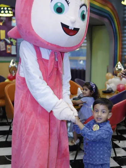 A young boy holds hands with the Masha mascot, a special guest character that sometimes visits Tingaland for events.
