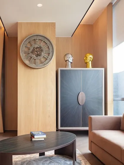In the Fineline Infra office lounge, we used light wood paneling and curated artifacts to create a relaxing atmosphere. The space includes a covered bar cabinet with a burst veneer pattern for entertaining clients.