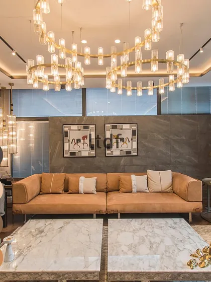 Just like picking an outfit, choosing colors for your space can impact your mood. This is the power of color psychology in design. Here, a warm tan sofa is complemented by marble tables and a stunning chandelier, creating an inviting vibe.