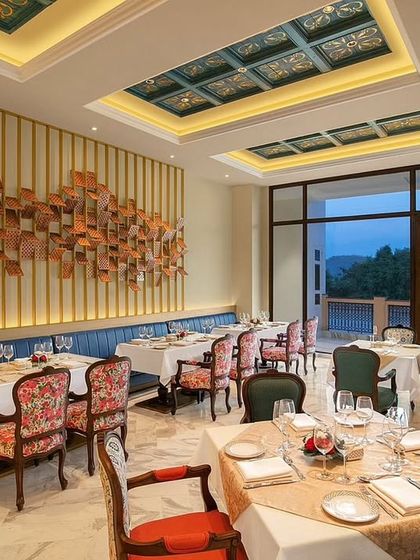 A different angle of the IHCL restaurant, highlighting the custom wall art and blue upholstered banquette. The design aims to tell a story of heritage and artistry, elevating the dining experience.