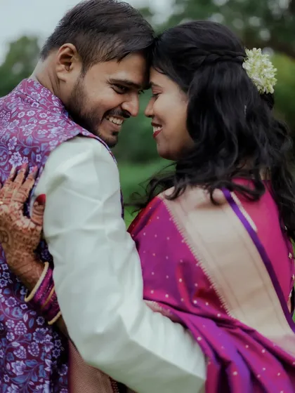 Milind and Anushree share a happy, intimate moment during their outdoor engagement photoshoot. The natural green background adds to the romantic feel.
