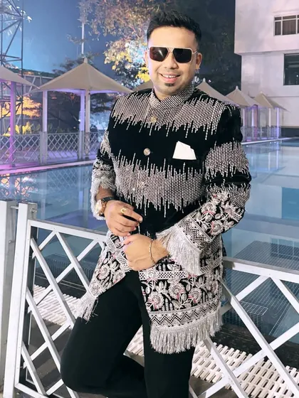 Posing by the pool in a heavily embroidered black and silver sherwani. This is a regal look, perfect for a grand destination wedding reception.