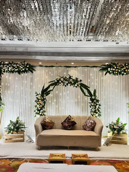 A simple yet stunning reception stage at Jaypee Siddharth. The decor uses a white floral arch and a neutral-toned sofa, perfect for an elegant, understated celebration.