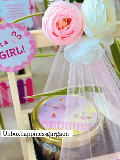 This close-up focuses on the "It's a Girl!" tag and the jar of treats, part of the plant-based favor set.