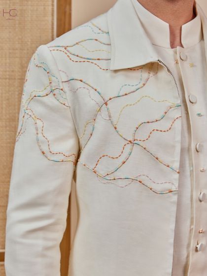 A close-up of the shacket's embroidery. The flowing, colorful lines add an artistic touch to the otherwise understated cream ensemble.