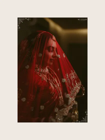 A moody and artistic portrait of the bride, her red veil creating a soft filter. This frame captures the quiet moments of reflection during her beautiful inter-cultural wedding day.