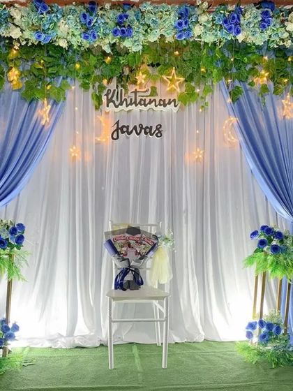 A full view of the celestial-themed ceremony backdrop. The combination of soft draping, floral arrangements on pedestals, and whimsical lighting elements creates a truly enchanting setting for any special occasion.