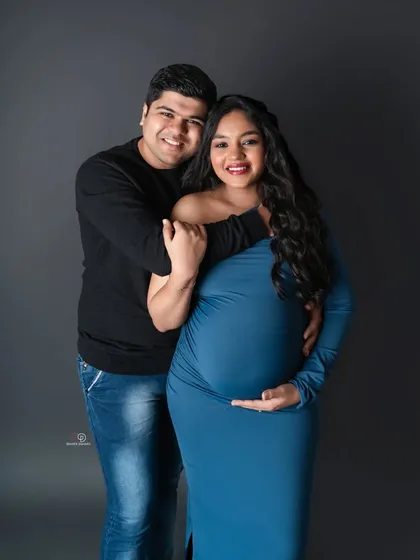 A beautiful bodycon gown in a striking blue. This classic studio portrait focuses on the couple's happy smiles and the beautiful shape of the baby bump.