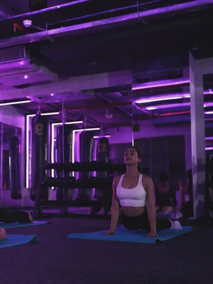 A moment of calm and strength during a yoga class in The Lab. The purple ambient lighting helps you focus inward as you hold poses, improving both your physical and mental balance.