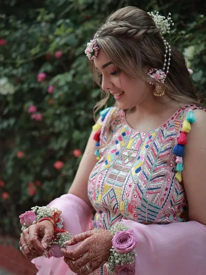 A close-up of the bride's Mehendi look. The floral jewelry and the tassels on her outfit add such a fun and festive touch.