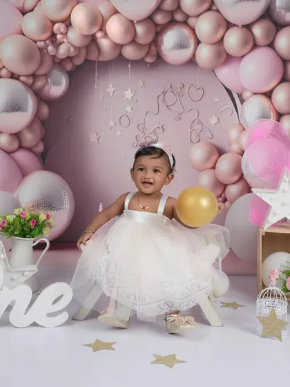 We captured the pure delight of this little one's first birthday. This milestone photoshoot features a custom-designed pink and silver balloon arch, creating a magical setting to celebrate such a special day.