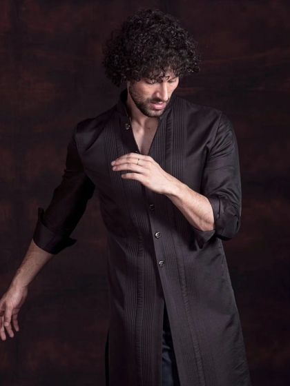 A longline black kurta with subtle pintuck detailing. This piece redefines elegance, where contemporary design meets traditional craftsmanship for a sharp, modern look.