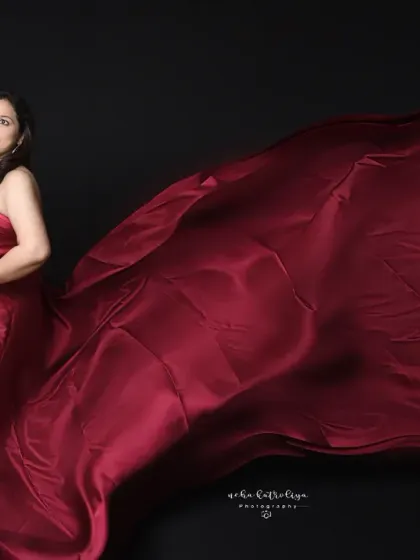 A classic and bold maternity portrait. The contrast of the rich red satin against a dark backdrop creates a powerful image, highlighting the beautiful silhouette of pregnancy.