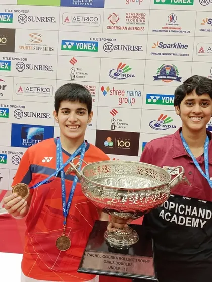 **A Champion's Smile.** Anmol Kharb with her partner, holding the impressive rolling trophy for the U-19 Girls' Doubles at the Krishna Khaitan Memorial tournament.