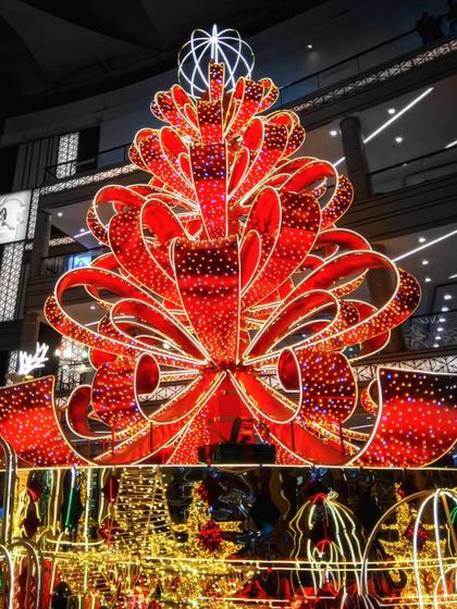 The festive spirit of Christmas in Mumbai. This low light shot captures a massive, brilliantly lit Christmas tree decoration made of red ribbons, showcasing the city's vibrant celebrations.