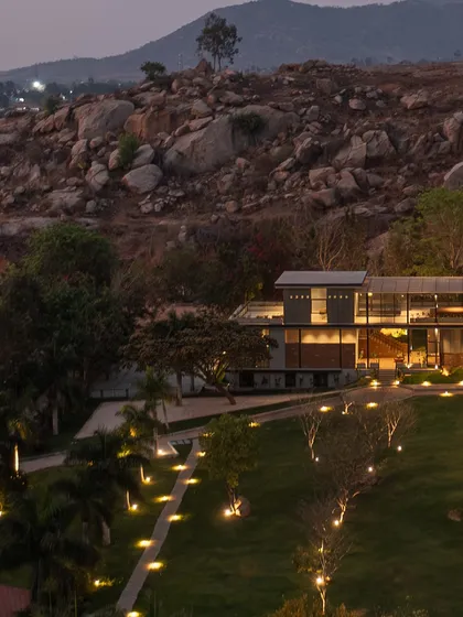 'The Earth' Experience Centre is designed to sit lightly on the land. This twilight view shows how the structure, with its illuminated pathways, integrates into the rocky Nandi Hills landscape, becoming a beacon of environmentally conscious design that respects its context.