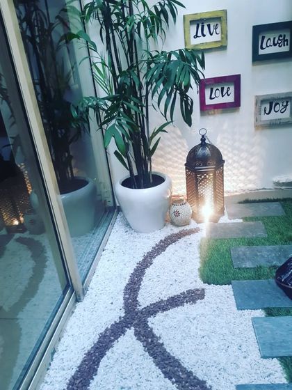 A beautiful corner of a patio featuring a pebble art pathway, a traditional lantern for mood lighting, and inspiring wall art.