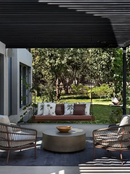We extend the living experience outdoors. This shaded patio at the Mango Orchard House, complete with comfortable seating and a gentle swing, was designed as a tranquil buffer zone for enjoying the garden, blurring the lines between inside and out.