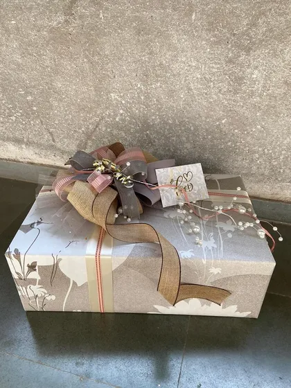 A beautifully wrapped gift box with a rustic-chic aesthetic. The nature-inspired wrapping paper is complemented by a burlap and pearl-accented bow, perfect for someone who appreciates understated elegance.