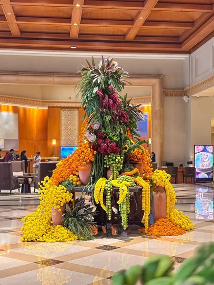 A full view of the marigold installation in the hotel lobby. The flowers seem to pour out from the center, creating a sense of movement and abundance that is both joyful and luxurious.
