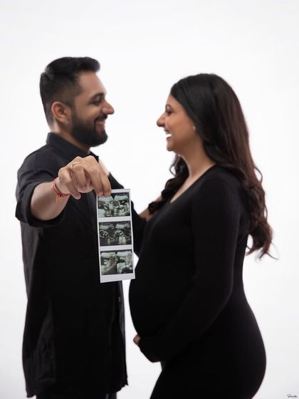 Sharing a laugh while holding up their sonogram pictures. This is a fun and personal way to announce and celebrate their growing family.