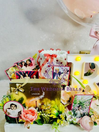 This grand birthday hamper features a light-up initial, a box of Lindor chocolates, and a beautiful arrangement of photos and flowers.