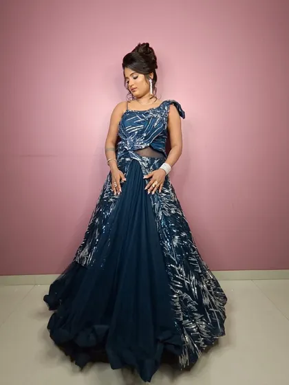 A full-length shot of the navy blue gown against a pink background, making the colors pop.