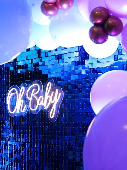 A close-up of the modern "Oh Baby" neon sign against a shimmering sequin wall. This combination creates a fantastic texture and glow, perfect for photos that pop.