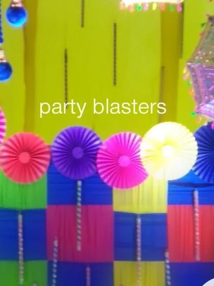 A close-up of the Dandiya Night decor, showing a photo wall made of colorful paper fans, umbrellas, and traditional hangings.