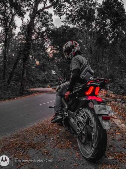 The same forest trail scene with a moody, desaturated edit, highlighting the red taillight of the Dominar.