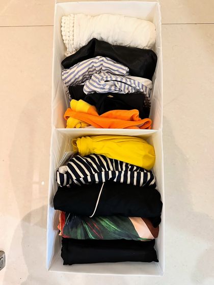 A top-down view of a bin with file-folded swimsuits. This method keeps them compact and allows you to see every pattern and color.