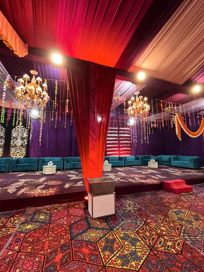 A comfortable lounge area with teal sofas set up on a raised platform, featuring intricate backdrops and a colorful patterned floor.