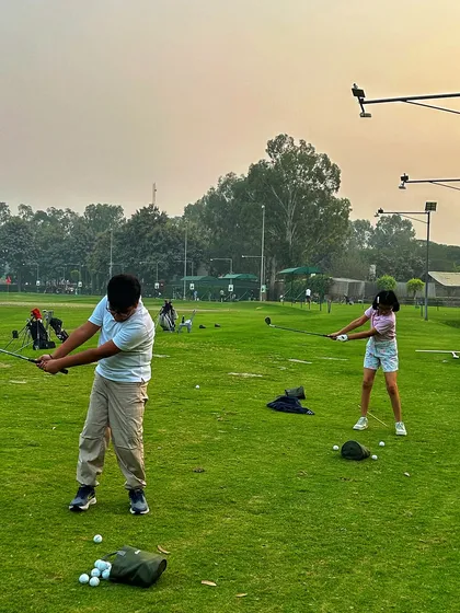 A young boy and girl practice their swings side-by-side on the grass, making golf a fun activity for all ages.