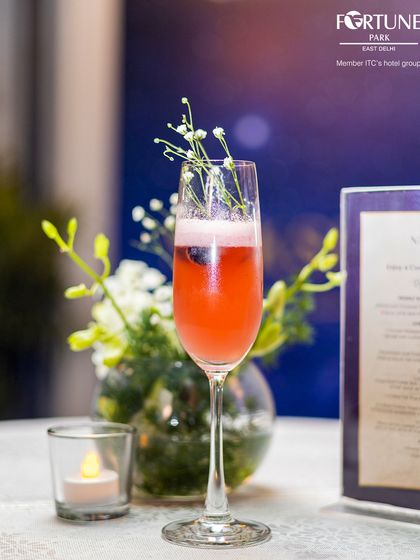 A delicate and refreshing cocktail served in a champagne flute, garnished with baby's breath for an extra touch of elegance.