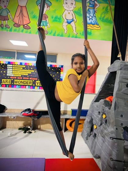 A demonstration of impressive flexibility, this young girl holds a perfect split while supported by the aerial silks.