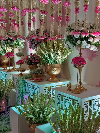 Another view of the decor tables, showcasing the lush greenery and pink blooms. The subtle uplighting adds a touch of modern drama to the traditional setup.