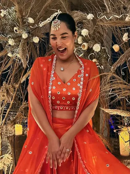 A candid moment of joy from the Diwali party. The guest's vibrant outfit perfectly complements the warm, rustic tones of our pampas grass and wood backdrop.