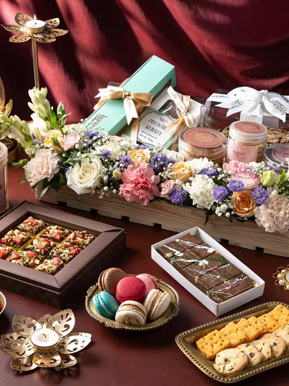 An opulent festive hamper overflowing with our artisanal creations, including beautifully packaged cookies, macarons, chocolate barks, and a stunning floral arrangement. This is the ultimate expression of thoughtful, luxurious gifting for any grand occasion.