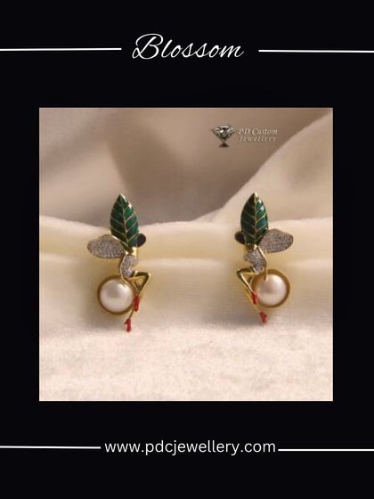 A pair of blossom-themed earrings in 18kt hallmarked gold. This artistic design features green enamel leaves, a central pearl, and sparkling diamonds.