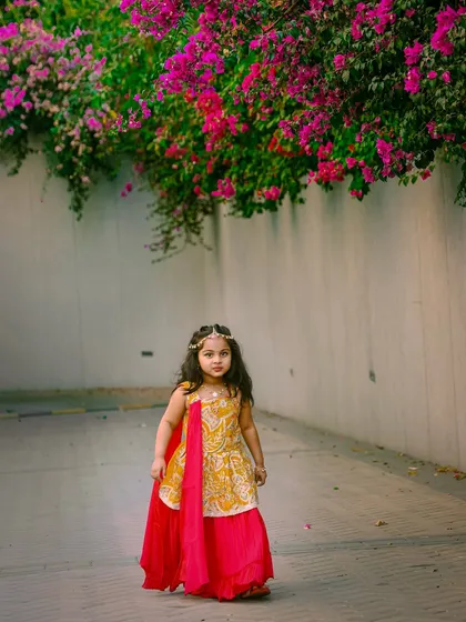 We take our studio outdoors to capture stunning portraits like this. The natural light and beautiful flowers perfectly complement this little princess in her elegant traditional dress.