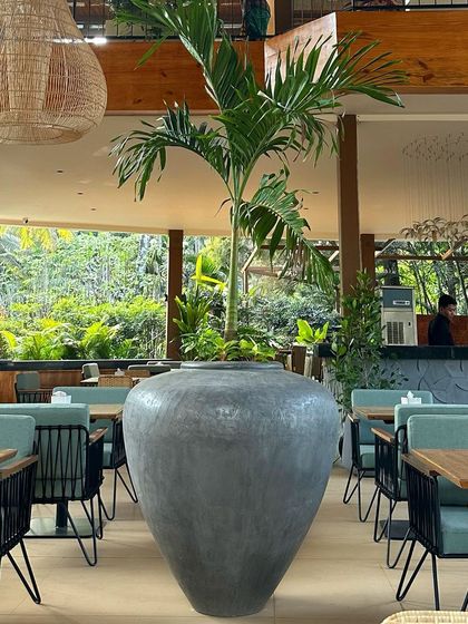 The 'Luhur' planter, standing at 110 CM, is a beautiful home for tall, lean trees in a modern setting like this restaurant.