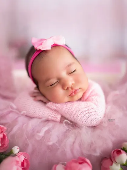 A classic newborn pose that highlights those chubby cheeks and sleepy smiles. Wrapped in a soft pink knit, this baby girl looks absolutely serene.