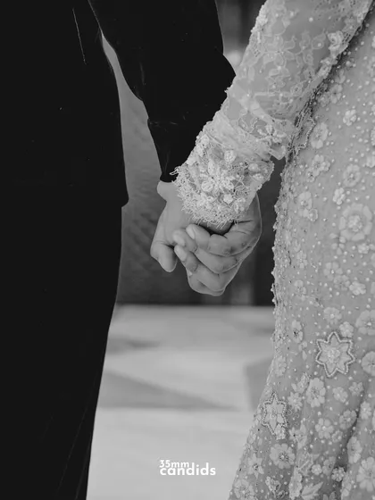 A black and white shot of a couple holding hands. The simplicity of the image emphasizes the strength of their connection and the promise to walk through life together.