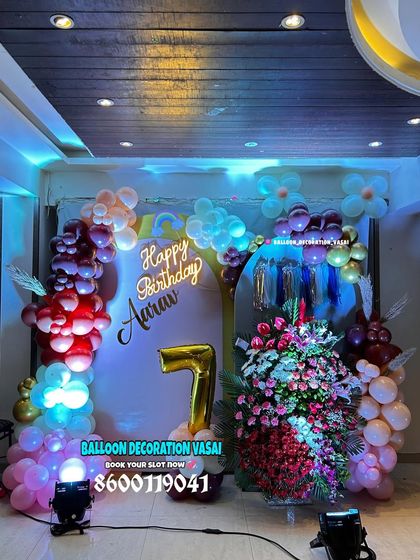 A 7th birthday party setup with a unique color palette and a large floral bouquet. The lighting adds a dramatic effect to the decor.